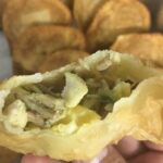 Golden, crispy Chilean changles wild mushroom empanadas arranged on a wooden table.