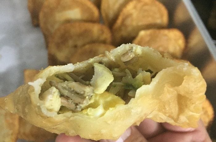 Golden, crispy Chilean changles wild mushroom empanadas arranged on a wooden table.