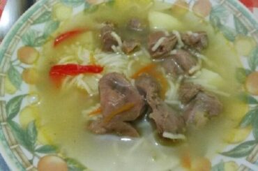 Chilean chicken gizzard soup with vegetables and noodles, served in a bowl.