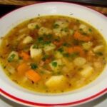 Chilean caldo de papas chilotas served in a clay bowl with harina tostada
