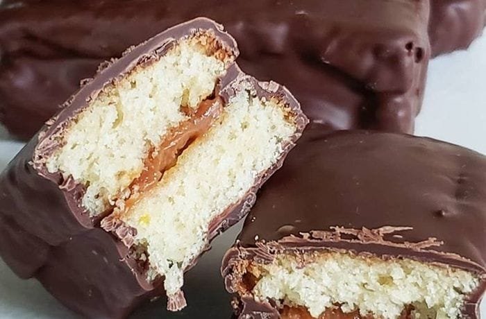 Rectangles of homemade Chilean chocman dipped in dark chocolate, with a visible manjar filling between the sponge layers.