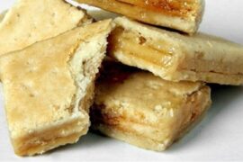 Layered Chilean chumbeque from Iquique, with a texture similar to nougat, on a wooden board ready to be cut.