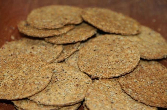 Round whole wheat cochayuyo crackers with dark flecks of seaweed on a wooden surface