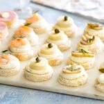 Chilean cold canapés on sandwich bread rounds with salmon, artichoke, and egg toppings