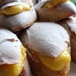 Golden Chilean conejitos sweet buns split open and filled with yellow pastry cream, dusted with powdered sugar