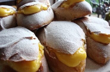 Golden Chilean conejitos sweet buns split open and filled with yellow pastry cream, dusted with powdered sugar