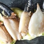 Cooked and cracked Chilean crab claws, served with scallion mayonnaise and lime as a seafood appetizer.