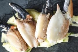 Cooked and cracked Chilean crab claws, served with scallion mayonnaise and lime as a seafood appetizer.