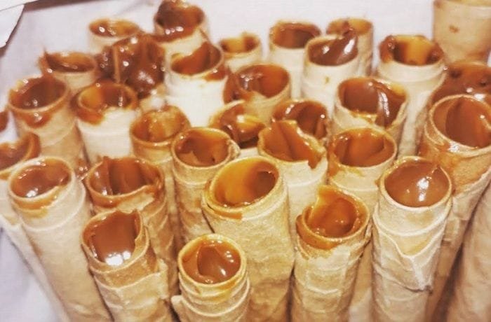 Chilean homemade cuchuflis filled with manjar and dipped in chocolate on a rack