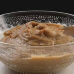 Chilean dulce de harina dorada, a thick glossy brown dessert in a clay bowl