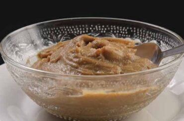 Chilean dulce de harina dorada, a thick glossy brown dessert in a clay bowl