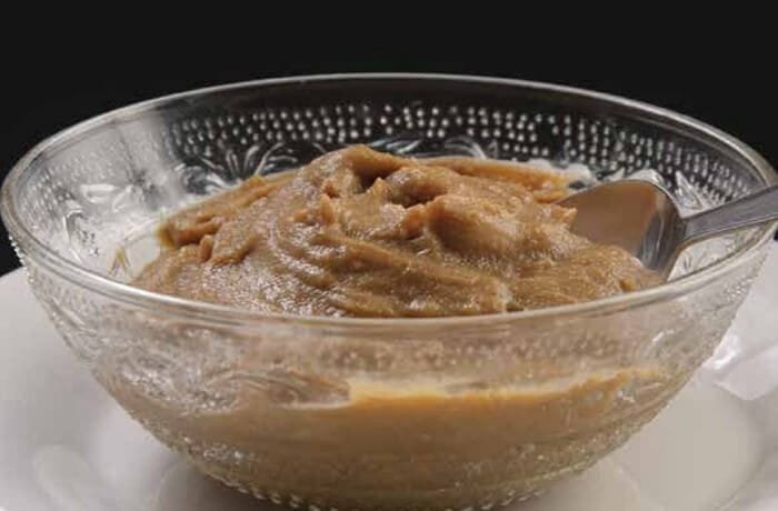 Chilean dulce de harina dorada, a thick glossy brown dessert in a clay bowl