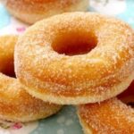 A platter of golden fried Chilean roscas, coated in granulated sugar, ready to serve.