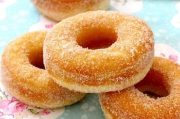 A platter of golden fried Chilean roscas, coated in granulated sugar, ready to serve.