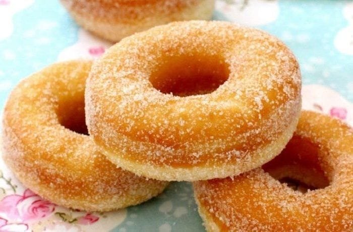 A platter of golden fried Chilean roscas, coated in granulated sugar, ready to serve.