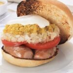 Open Chilean gorda completa sandwich with a thick split sausage, sauerkraut, tomato, and mayonnaise
