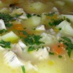 A deep bowl of Chilean loco carbonada with potatoes and carrots, garnished with fresh parsley.