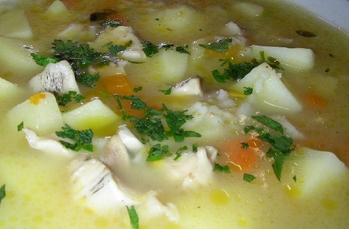 A deep bowl of Chilean loco carbonada with potatoes and carrots, garnished with fresh parsley.