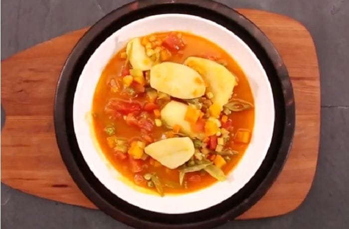 Hot Chilean locro falso with potatoes, squash, and corn in a deep clay bowl