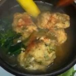 Hot Chilean machos ahogados soup in a clay bowl, with flour and egg dumplings floating in the broth