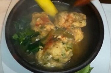 Hot Chilean machos ahogados soup in a clay bowl, with flour and egg dumplings floating in the broth