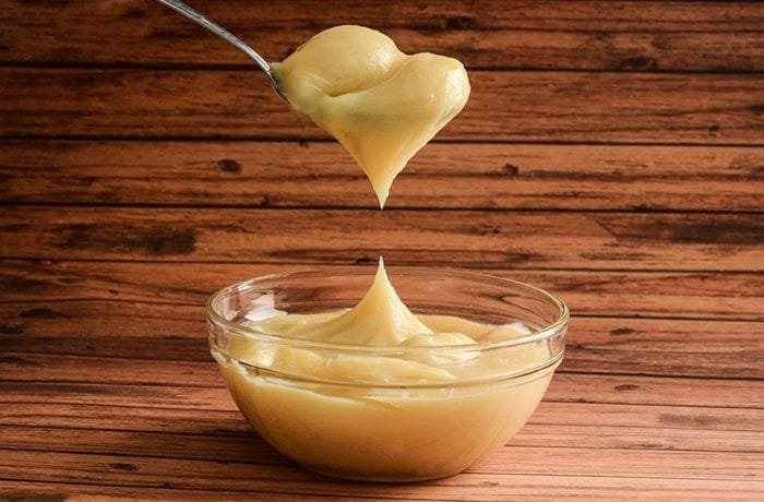 Homemade Chilean manjar, dark caramel colored dulce de leche in a glass bowl