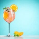 Tall wine glass with the Chilean Maracuzzotti cocktail over ice, topped with an orange slice