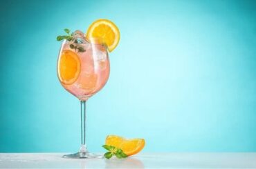 Tall wine glass with the Chilean Maracuzzotti cocktail over ice, topped with an orange slice