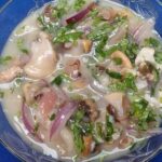 Chilean cold mariscal frio served in a cocktail glass with clams, scallops, shrimp, and reineta fish, garnished with cilantro.