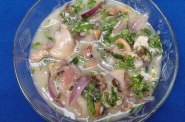 Chilean cold mariscal frio served in a cocktail glass with clams, scallops, shrimp, and reineta fish, garnished with cilantro.