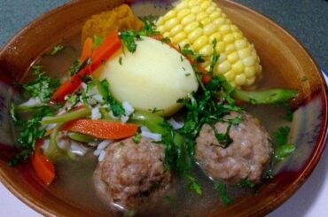 Chilean cazuela de albondigas, meatball soup with potato, squash, and corn in a deep bowl