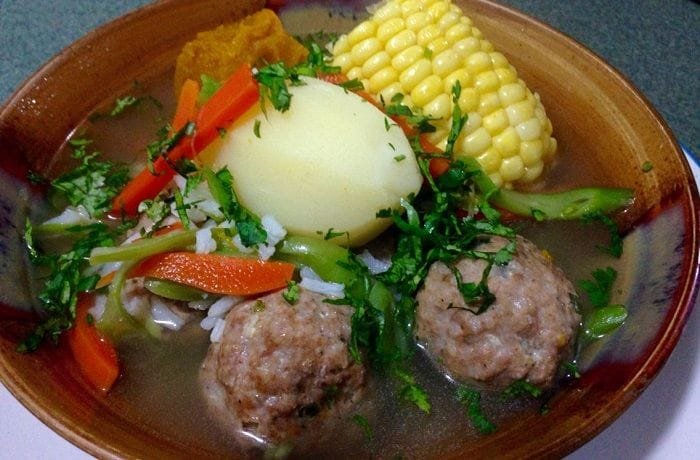 Chilean cazuela de albondigas, meatball soup with potato, squash, and corn in a deep bowl