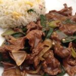 Plate of Chilean Mongolian beef stir-fried with spring onions in a dark sauce, served with chaufan rice