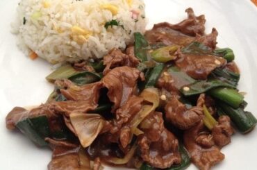 Plate of Chilean Mongolian beef stir-fried with spring onions in a dark sauce, served with chaufan rice