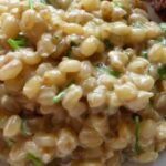 A plate of creamy mote risotto topped with Parmesan cheese, served in a deep dish.