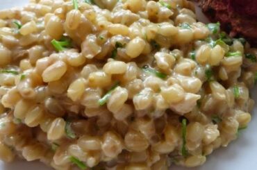 A plate of creamy mote risotto topped with Parmesan cheese, served in a deep dish.