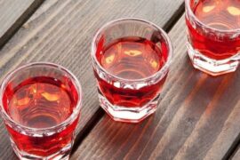 Small glass of homemade Chilean murtado, a reddish murtilla berry liqueur.