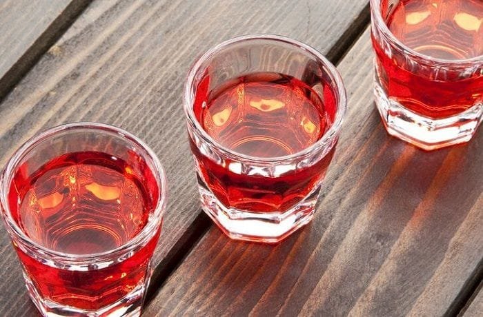 Small glass of homemade Chilean murtado, a reddish murtilla berry liqueur.