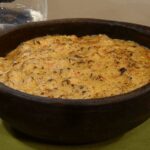 Creamy Chilean octopus chupe gratinated with cheese and sprinkled with parsley in a clay dish