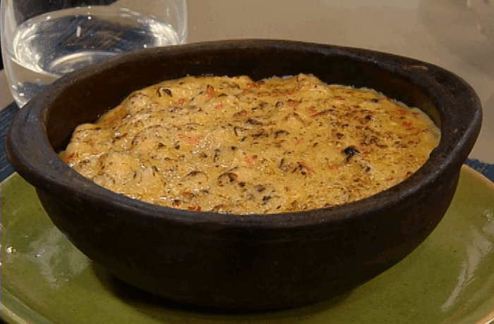 Creamy Chilean octopus chupe gratinated with cheese and sprinkled with parsley in a clay dish
