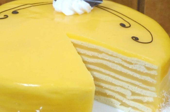 Tall Chilean orange pancake cake in thin layers, covered with orange cream and chocolate decoration