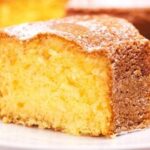 Freshly baked Chilean orange sponge cake dusted with powdered sugar on a rustic wooden board