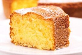 Freshly baked Chilean orange sponge cake dusted with powdered sugar on a rustic wooden board