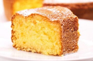 Freshly baked Chilean orange sponge cake dusted with powdered sugar on a rustic wooden board