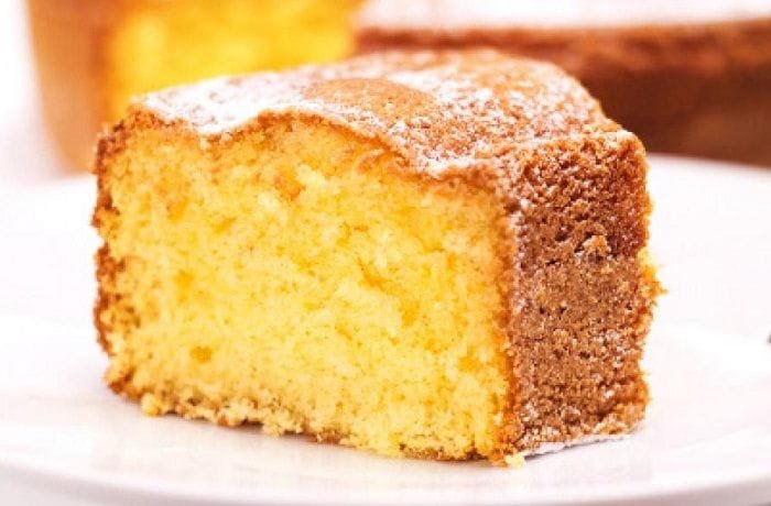 Freshly baked Chilean orange sponge cake dusted with powdered sugar on a rustic wooden board