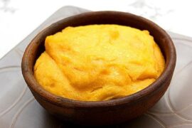 Chilean pastel de chuchoca served in an individual clay dish with a golden top layer.