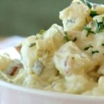 Bowl of Chilean potato salad with mayonnaise, diced celery and onion, sprinkled with fresh chives