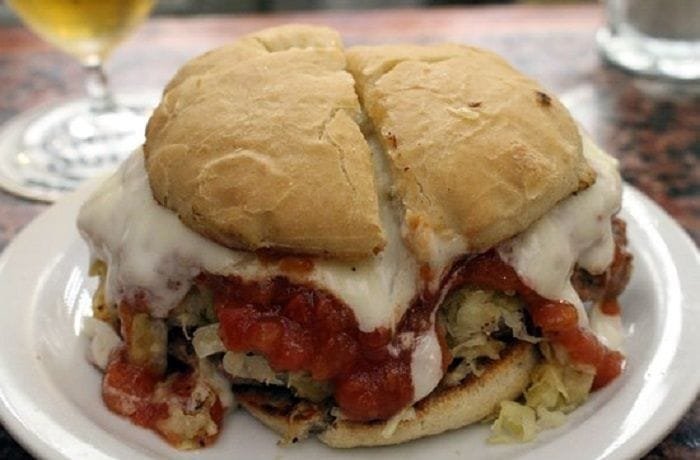 Chilean rumano completo sandwich with beef and pork patty, tomato sauce, sauerkraut, and mayonnaise