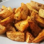 Tray of rustic skin on roasted potatoes, golden and seasoned with oregano and merken