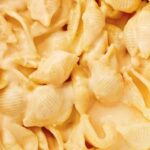A plate of caracoquesos, shell-shaped pasta covered in a creamy melted cheese sauce.